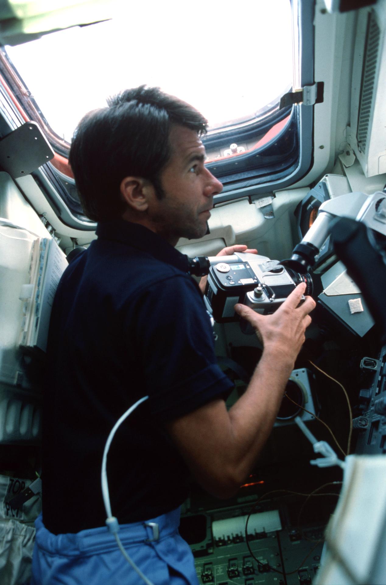 View of astronaut William B. Lenoir holding a camera as he looks out the window on Space Shuttle Columbia