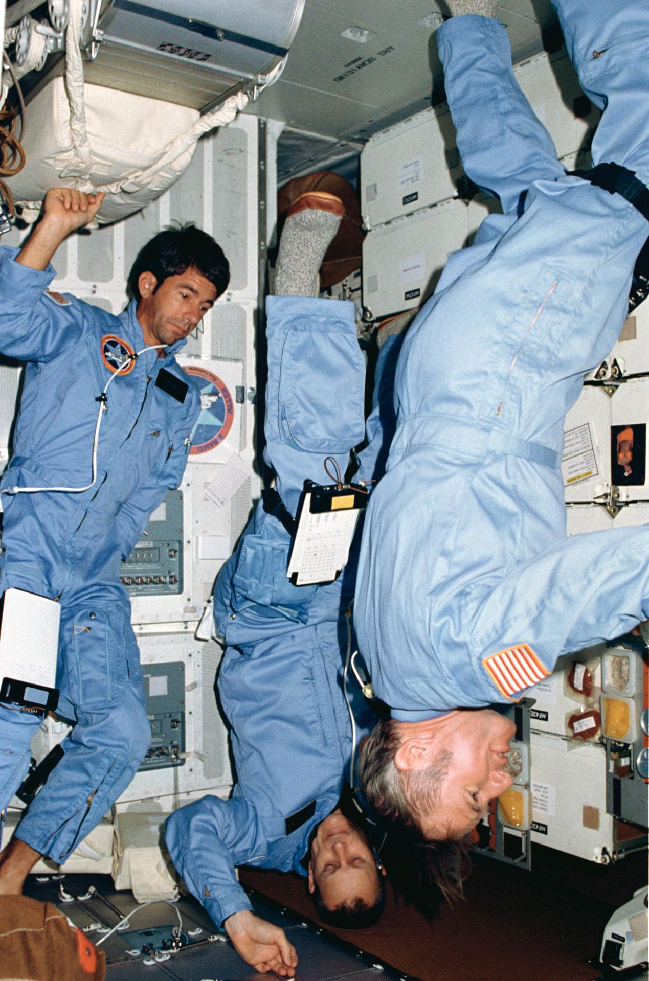 Three STS-5 astronauts oriented in different directions on space shuttle Columbia while in Earth orbit