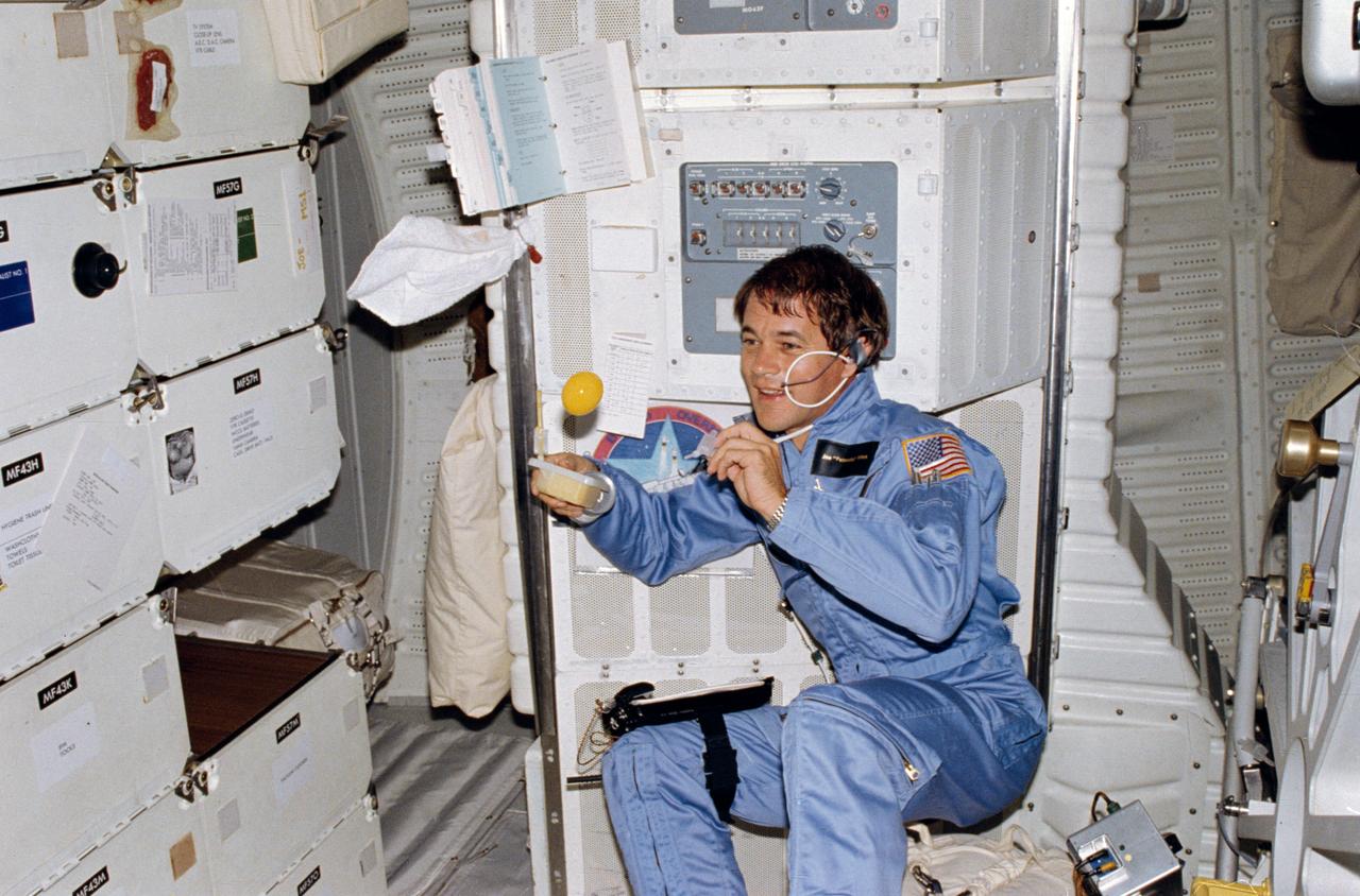 STS005-04-128 (11-15 Nov. 1982) --- Astronaut Joseph P. Allen IV, STS-5 mission specialist, watches as an orange juice globule floats freely moments after he created the ball using the straw portion (left hand) of his beverage dispenser (right hand) onboard the Earth-orbiting space shuttle Columbia. Dr. Allen is in middeck area of the Columbia, marking its first operational (non-test) flight in Earth orbit. Photo credit: NASA