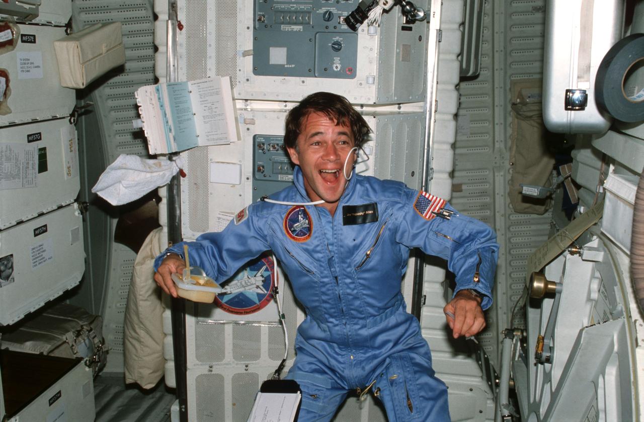 STS005-04-134 (11-16 Nov. 1982) --- Astronaut Joseph P. Allen IV, STS-5 mission specialist, uses beverage container and drinking straw, experiments with microgravity characteristics of orange juice on middeck in front of the Development Flight Instrument (DFI) unit and forward lockers. Allen laughs as he watches the results of his experimentation. Photo credit: NASA