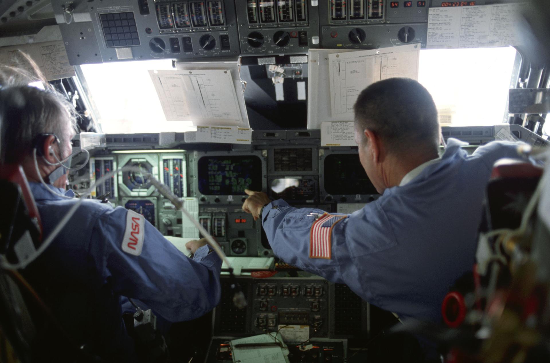 Vance Brand and Robert Overmyer work at the forward flight deck during theSTS-5 mission.