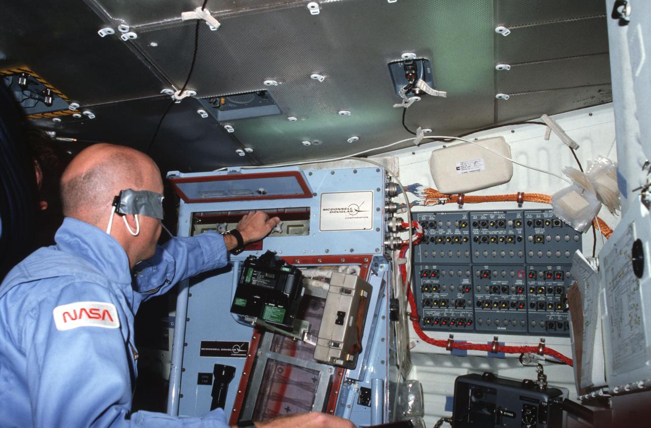 STS006-03-381 (4-9 April 1983) --- Astronaut F. Story Musgrave, STS-6 mission specialist, monitors the activity of a sample in the continuous flow electrophoresis system (CFES) aboard the Earth-orbiting space shuttle Challenger. Dr. Musgrave is in the middeck area of the spacecraft. He has mounted a 35mm camera to record the activity through the window of the experiment. This frame was also photographed with a 35mm camera. Photo credit: NASA