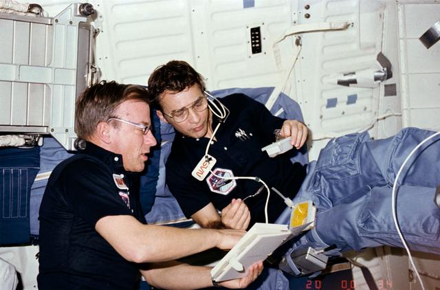 NASA image: MS Peterson eats while reviewing procedures with Commander Weitz on middeck