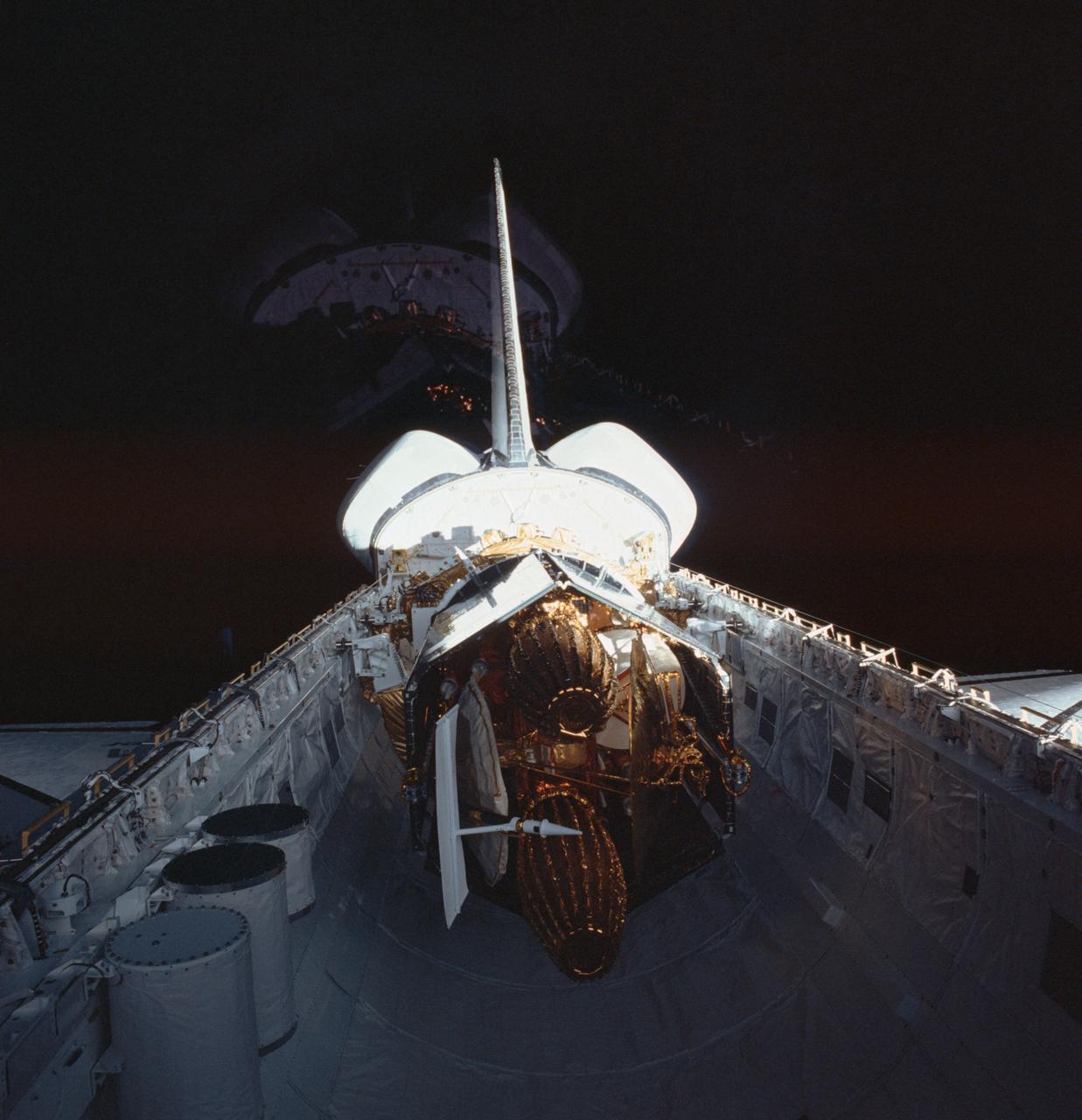 STS006-38-844 (4 April 1983) --- The stowed tracking and data relay satellite (TDRS) and its inertial upper stage (IUS) are seen in duplicate in this 70mm frame taken by the STS-6 crew aboard the Earth-orbiting space shuttle Challenger on its first day in space. A reflection in the aft window of the flight deck resulted in the mirage effect of the “second” TDRS. The three canisters in the aft foreground contain experiments of participants in NASA’s STS getaway special (GAS) program. Onboard the second reusable shuttle for this five-day flight were astronauts Paul J. Weitz, Karol J. Bobko, Dr. F. Story Musgrave and Donald H. Peterson. Photo credit: NASA