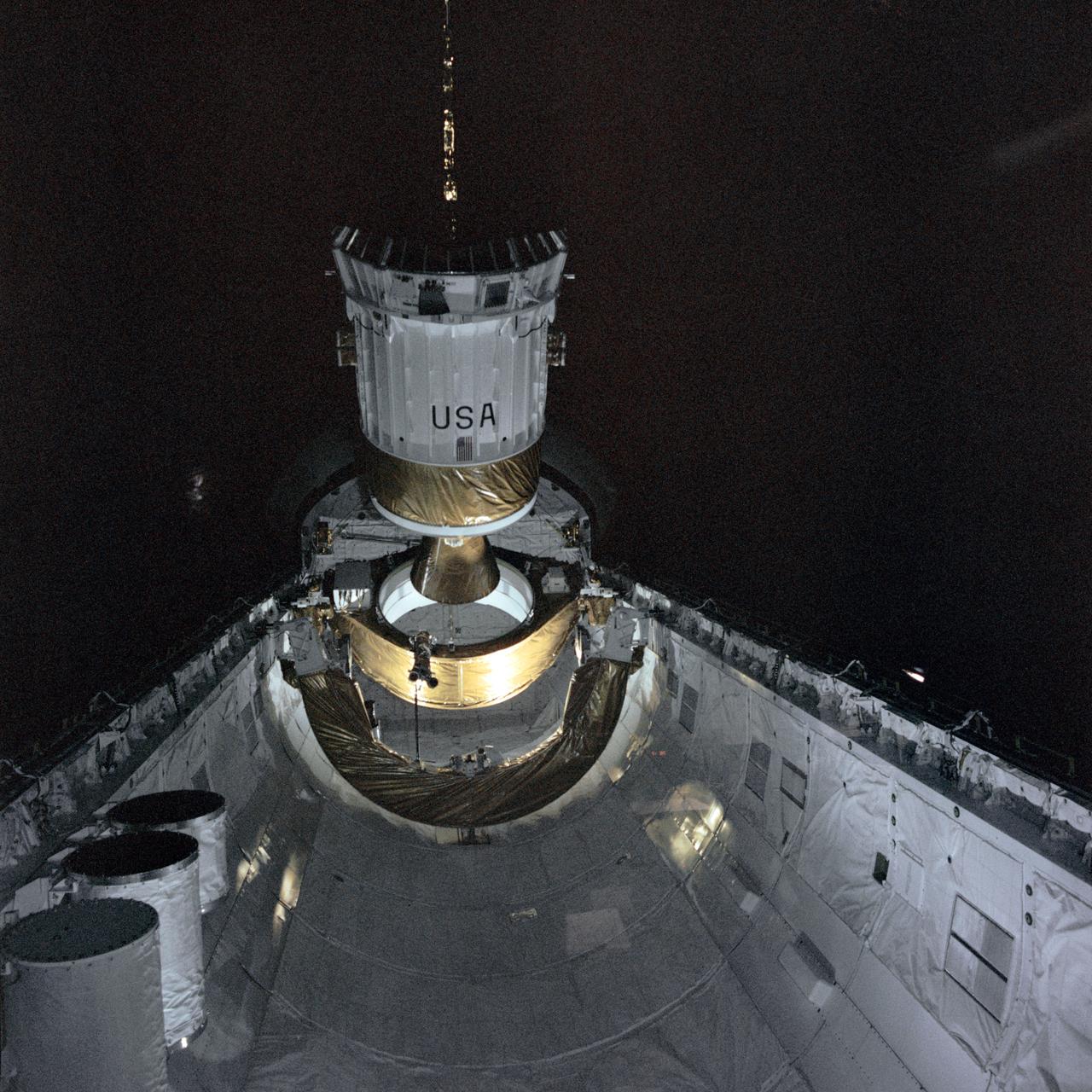 STS006-38-894 (4 April 1983) --- The tracking and data relay satellite (TDRS) leaves the 18-meter (60-ft) long cargo bay of the Earth-orbiting space shuttle Challenger about ten hours following launch of NASA’s second reusable space vehicle. The inertial upper stage (IUS) which gives power necessary to place the TDRS in its desired orbit is clearly seen in this view, photographed with a 70mm camera aimed through the aft flight deck windows of the Challenger. The cylindrical canisters in the left foreground contain scientific experiments from subscribers to NASA’s getaway special (GAS) program. Photo credit: NASA