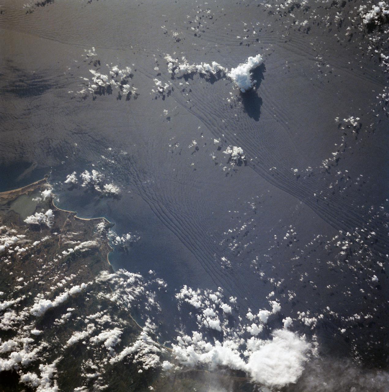 STS007-05-245 (18-24 June 1983) --- A rare view of internal waves in the South China Sea.  Several different series of internal waves are represented in the 70mm frame,  exposed with a handheld camera by members of the STS-7 astronaut crew aboard the Earth-orbiting Challenger.  The land area visible in the lower left is part of the large island of Hainan, China.