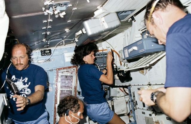 NASA image: STS-7 crewmembers during meal preparation on middeck