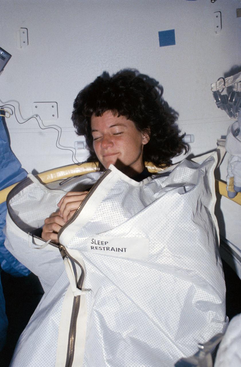 STS007-26-1438 (18-24 June 1983) --- Astronaut Sally K. Ride, mission specialist, was captured at her sleep station in the Space Shuttle Challenger's middeck by a fellow crew member using a 35mm camera.  This method of sleep is just one used by the 20 astronauts who have now flown aboard NASA's first two Space Shuttle Orbiters.  Some astronauts choose to sleep in various positions with either their feet or upper bodies or both anchored and others elect to use the sleep restraint device demonstrated here by Dr. Ride.