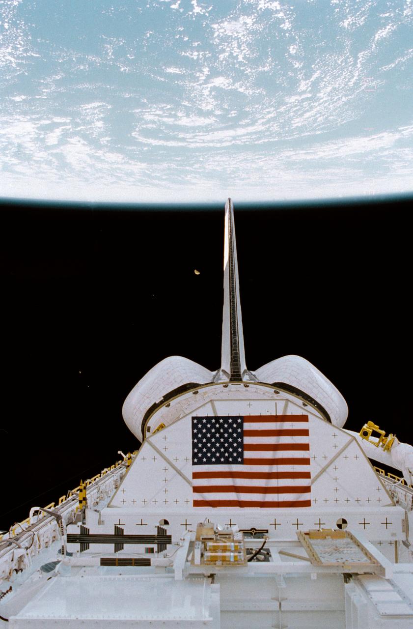 STS008-02-0041 (30 Aug-5 Sept 1983) --- An astronaut's eye view of two thirds of the cargo bay, the white and blue horizon scene of the Earth, and a gibbous moon was recorded on 35mm film from the aft flight deck of the Earth-orbiting Space Shuttle Challenger. The payload flight test article (PFTA) appears to be awaiting its heavy workout schedule in the middle of the bay.