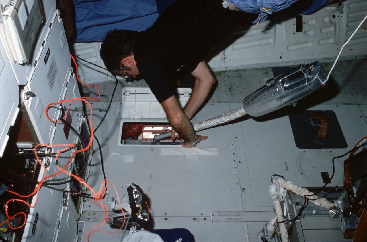 STS008-13-336 (5 Sept 1983) --- On middeck, Richard M. Truly, STS-8 commander, uses vacuum cleaner to remove debris from air revitalization system (ARS) filter assembly. Open panel on middeck floor is the ARS access panel.