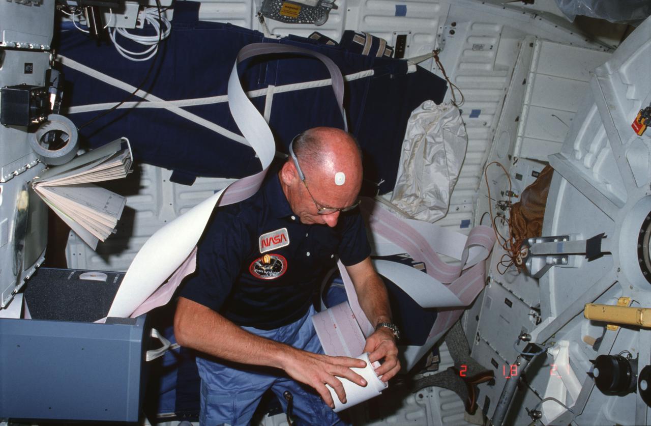 STS008-14-378 (30 Aug-5 Sept 1983) --- Astronaut William E. Thornton, a very busy mission specialist conducting a great deal of bio-medical experimentation, checks a prolific roll of data in the mid deck of the Earth-orbiting Space Shuttle Challenger.  The electrode on Dr. Thornton’s forehead indicates that his four crewmates were not his only test subjects during the extensive test on this six-day flight.