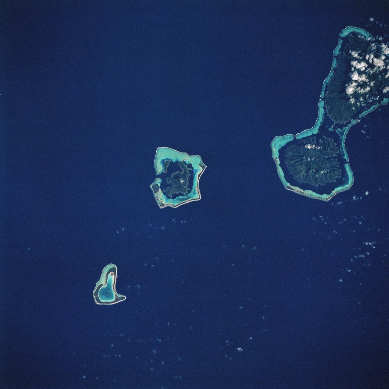 STS008-32-748 (30 Aug-5 Sept 1983) --- Bora-Bora, with its wide-fringing reef, stands out in the center of this photographed, taken over the Society Island chain from the Earth-orbiting Space Shuttle Challenger on its third spaceflight. In the upper left corner are the islands of Raiatea and Tahaa. The ancient volcano islands are very slowly sinking into the oceanic crust, while coral growth maintains a reef platform.