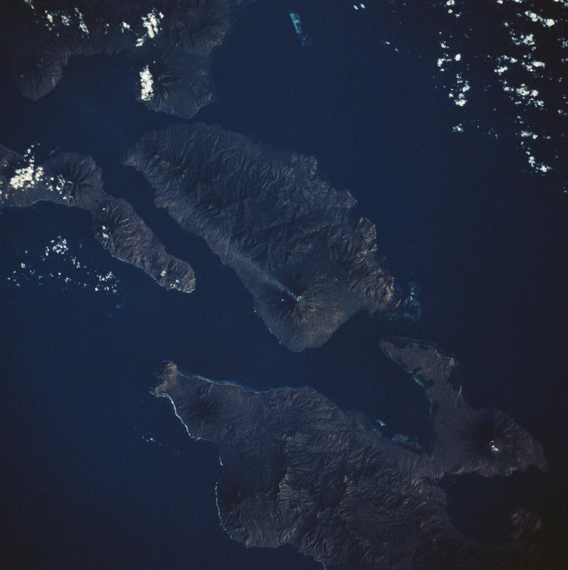 An active 5,500 foot high volcano on Adonara Island in Indonesia leaves a 30 mile long visible trail of smoke. The surrounding islands are Flores (lower right) Solor (right edge) and Lomblen (upper center). This photograph was made from the Earth orbiting Space Shuttle Challenger on its third mission.