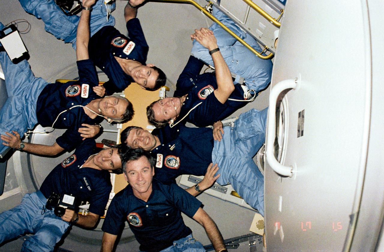 STS009-126-441 (28 Nov 1983) --- The six crewmembers of STS-9 position themselves in a star bust-like cluster in the aft end cone of Spacelab aboard the Shuttle Columbia. Clockwise, beginning with John W. Young, are Ulf Merbold, Owen K. Garriott, Brewster H. Shaw, Jr., Byron M. Lichtenberg and Robert A.R. Parker.