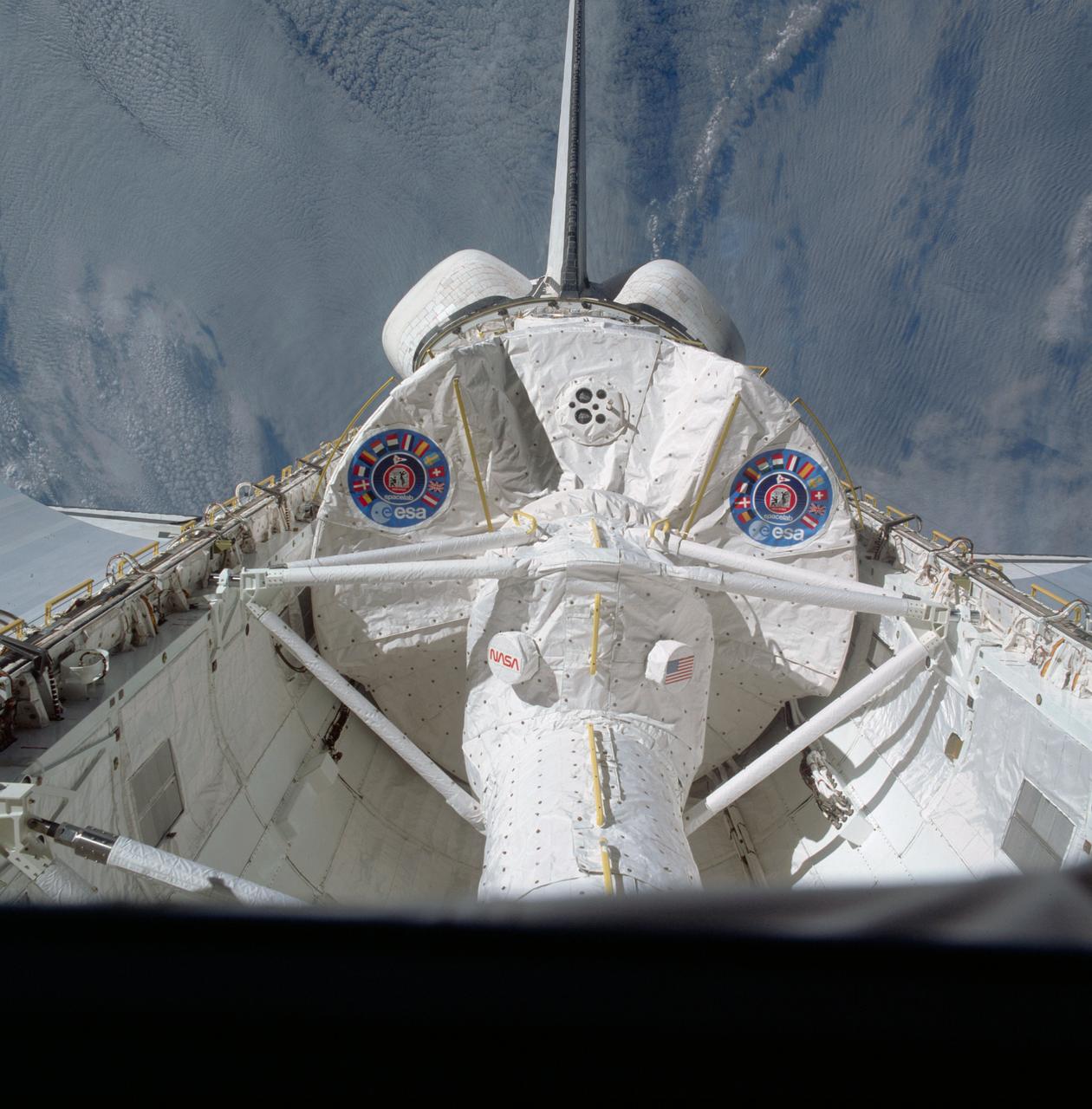 STS009-32-1112 (28 Nov-8 Dec 1983) --- A handheld Hasselblad camera was aimed through the aft windows on the flight deck of Columbia for this initially released scene of the active Spacelab module in the cargo bay.  The docking tunnel, leading from the shirt-sleeve environment of the orbiter to the equally comfortable environment of Spacelab, is in the foreground.