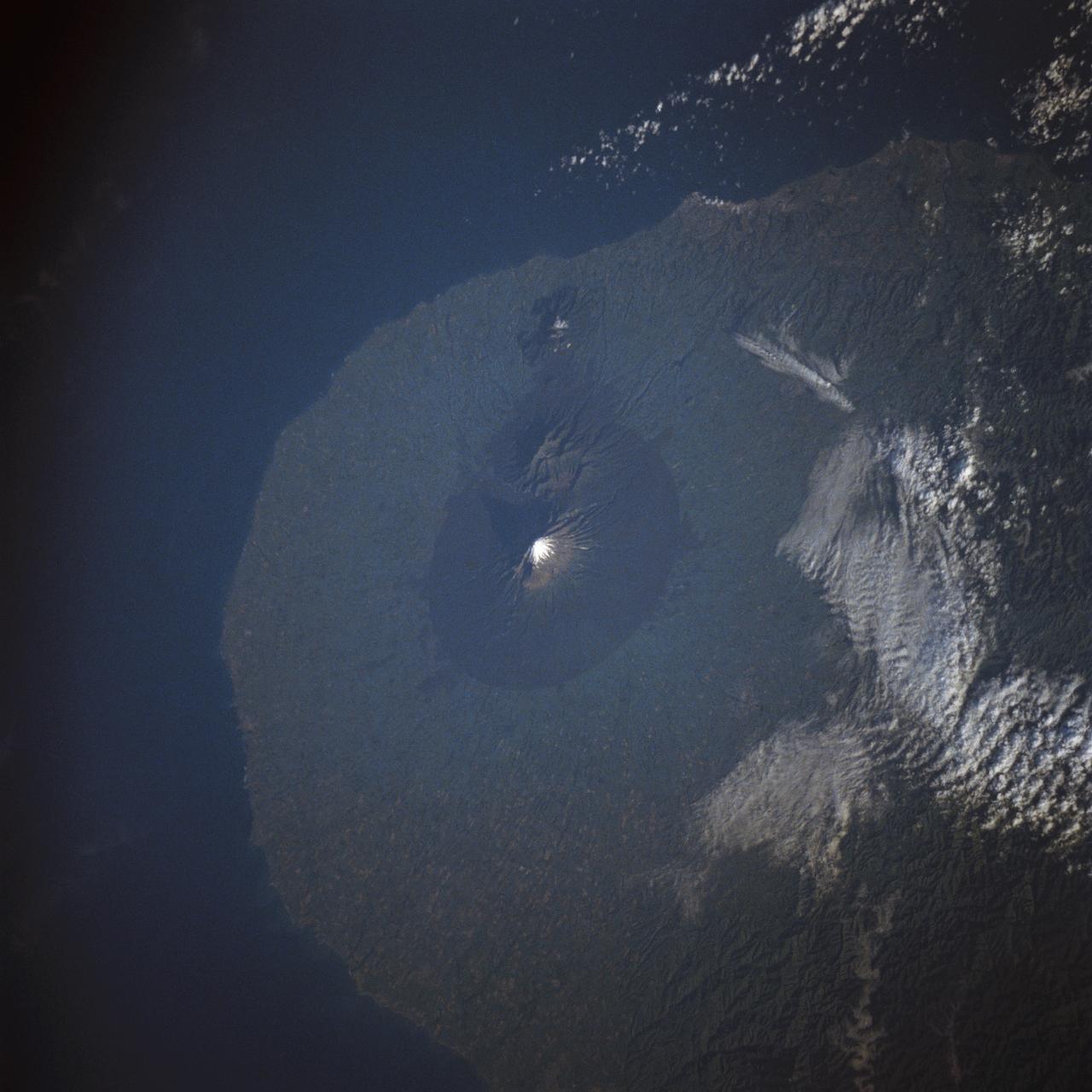 STS009-40-2574 (28 Nov-8 Dec 1983) --- New Zealand?s Mount Egmont volcano rises 8300 ft (2520 meters) out of the Tasman Sea and has been designated as a national park.  It is on the North Island, 125 miles (200 Km) SSW of Auckland.  The border fence of the national park is clearly seen because the lighter green area surrounding it is a grazing range.