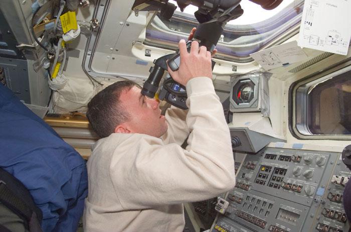 STS102-E-5008 (9 March 2001) --- Astronaut James M. Kelly, pilot,   aims a camera through an overhead window on the aft flight deck of the  Earth-orbiting Space Shuttle Discovery   late on the initial day in space for   the STS-102 crew.