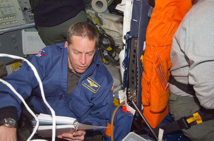 STS102-E-5014 (9 March 2001) --- Astronaut James D. Wetherbee, mission commander, refers to a manual during  activity on the initial day in space for the STS-102 astronauts and cosmonaut.  Wetherbee is behind the commander's station on the flight deck of the Space Shuttle Discovery.