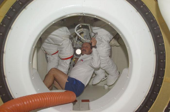 STS102-E-5015 (9 March 2001) --- Cosmonaut Yury V. Usachev, STS-102 mission specialist representing Rosaviakosmos, checks two extravehicular mobility unit (EMU) space suits in the airlock of the Space Shuttle Discovery.  In less than two days, the suits will be in use by two of the future Expedition Two crew members.  Usachev is scheduled to  assume the commander's position soon onboard the orbiting outpost.