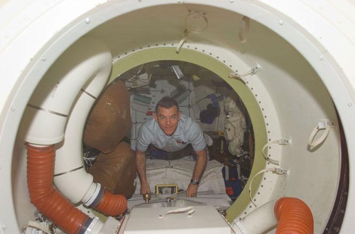 STS102-E-5016 (9 March 2001) --- Astronaut James S. Voss, STS-102 mission specialist, perhaps looks toward his  scheduled space walk as he floats on the mid deck of the Space Shuttle Discovery, not far from his space suit.  At some point following the scheduled linkup of the Discovery and the International Space Station (ISS), Voss will assume the role of flight engineer for the three-person Expedition Two crew assigned as replacements for the Expedition One trio that has been on the station since early November 2000.