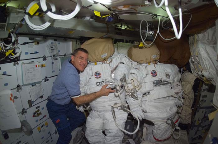 STS102-E-5070  (10 March 2001) --- Astronaut James S. Voss, STS-102 mission specialist, is pictured with both Extravehicular Mobility Unit (EMU) space suits designated for this flight's  extravehicular activity (EVA).  Voss  is one of two astronauts assigned to space walk duties after the Space Shuttle Discovery  and the International Space Station (ISS) link in Earth orbit.  The photograph was recorded with a digital still camera on Discovery's mid deck.