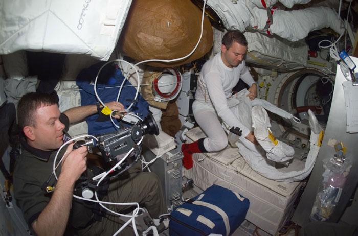 STS102-E-5160 (13 March 2001) --- Astronaut James M. Kelly (left),  pilot,  documents mid deck preparations for the second STS-102 space walk.  Astronaut Paul W. Richards, mission specialist, dons his extravehicular mobility unit (EMU) space suit at right. The photograph was taken with a digital still camera.