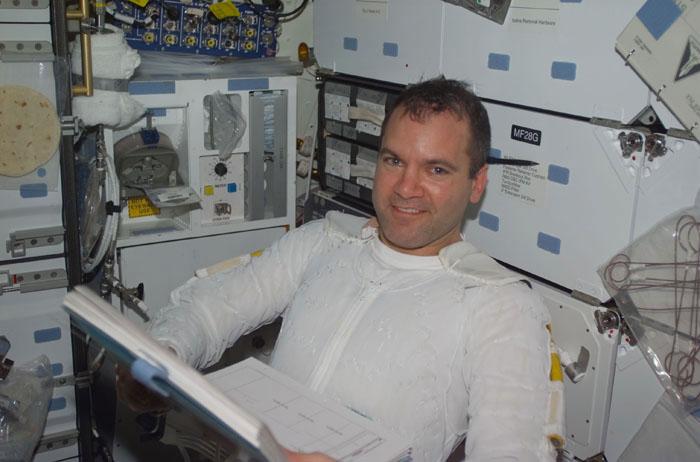 STS102-E-5207 (13 March 2001) --- Astronaut Paul W. Richards, following the second STS-102 space walk, still wears the thermal undergarment for his extravehicular mobility unit  (EMU) space suit, as he looks over flight data near the galley on Discovery's mid deck.  The photograph was taken with a digital still camera.