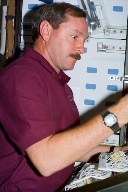 S103-E-5007 (20 December 1999) --- Astronaut Curtis L. Brown, mission commander, retrieves supplies from a mid deck stowage locker onboard the Space Shuttle Discovery.  He and six other astronauts will spend a great deal of time later in the week performing a variety of service tasks on the Hubble Space Telescope (HST). As commander of the mission, Brown will remain inside Discovery while several of the other crew members will perform service tasks on HST. The photo was taken with an electronic still camera (ESC) at 16:12:27 GMT, Dec. 20, 1999.