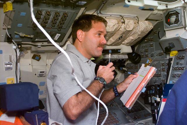 S103-E-5016 (20 December 1999) --- Astronaut John M. Grunsfeld, mission specialist, looks over a flight plan on Space Shuttle Discovery's flight deck while communicating with ground controllers on flight day 1. The photo was taken with an electronic still camera (ESC) at 16:21:29 GMT, December 20, 1999.
