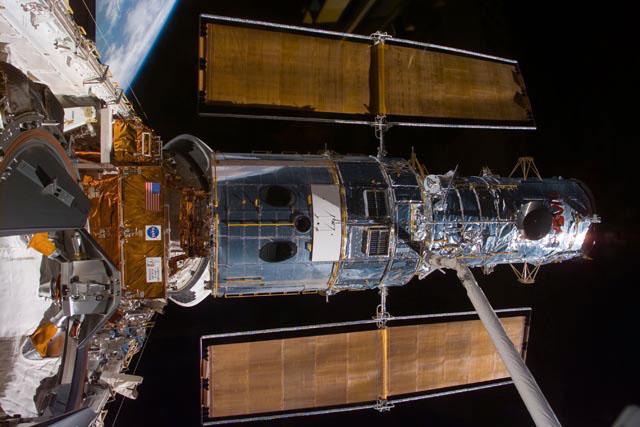 S103-E-5162 (21 December 1999) --- This electronic still camera's view and others in this series showing the Hubble Space Telescope (HST)being berthed in Discovery's bay were recorded during and soon after capture; and they were downlinked at the completion of the mission's first space walk on the following day by the busy STS-103 astronauts. The image was recorded at 19:47:22 GMT, Dec. 21, 1999.