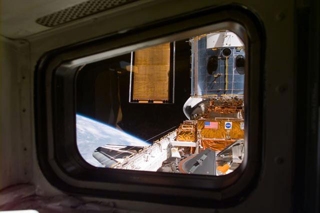 S103-E-5166 (21 December 1999) --- This electronic still camera's view and others in this series showing the Hubble Space Telescope (HST) berthed in Discovery's bay were recorded soon after capture and downlinked at the completion of the mission's first space walk on the following day by the busy STS-103 astronauts. The image was recorded through Discovery's starboard side aft flight deck window at 19:48:24 GMT, Dec. 21, 1999.