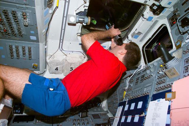 S103-E-5201 (21 Dec. 1999) --- Astronaut John M. Grunsfeld, uses a pair of binoculars to view the distant Hubble Space Telescope (HST) several hours prior to its capture by the Space Shuttle Discovery. The photo was taken with an electronic still camera (ESC) at  12:45.19 GMT, Dec. 21, 1999.