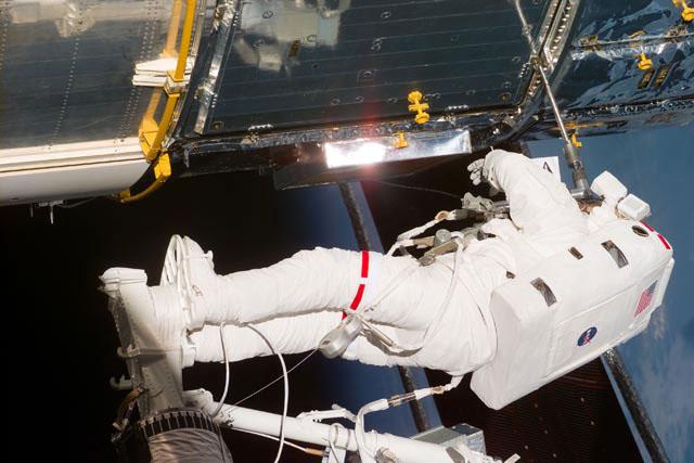 S103-E-5294 (23 Dec. 1999) --- Astronaut C. Michael Foale, standing on the end of Discovery's remote manipulator system (RMS), which had hoisted him to a task station on the Hubble Space Telescope (HST), uses a tool during the second spacewalk for the STS-103 mission. Astronauts Foale and Claude Nicollier are the second pair of STS-103 mission specialists to abandon the shirt-sleeve environment of Discovery's cabin for several hours' tasks on this the third NASA servicing mission to HST. The photo was taken with an electronic still camera (ESC). Photo credit: NASA