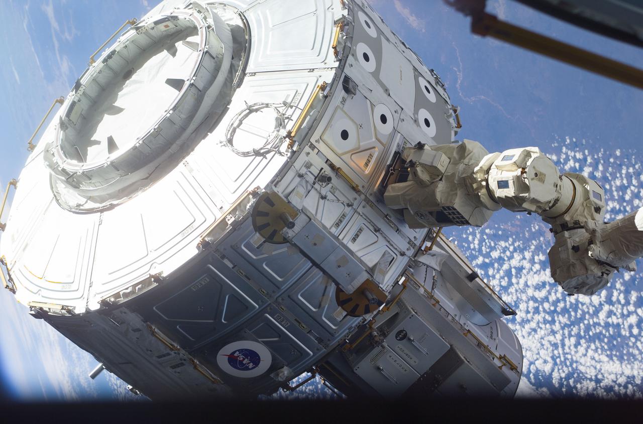 S104-E-5065 (15 July 2001) --- The newly-installed Candarm2, Space Station Remote Manipulator System (SSRMS), controlled by Susan J. Helms, Expedition Two flight engineer, maneuvers the Quest Airlock in the proper position to be mated onto the starboard side of Unity Node 1 during the first extravehicular activity (EVA) of the STS-104 mission.  The Earth backdrops this image, exposed with a digital still camera.