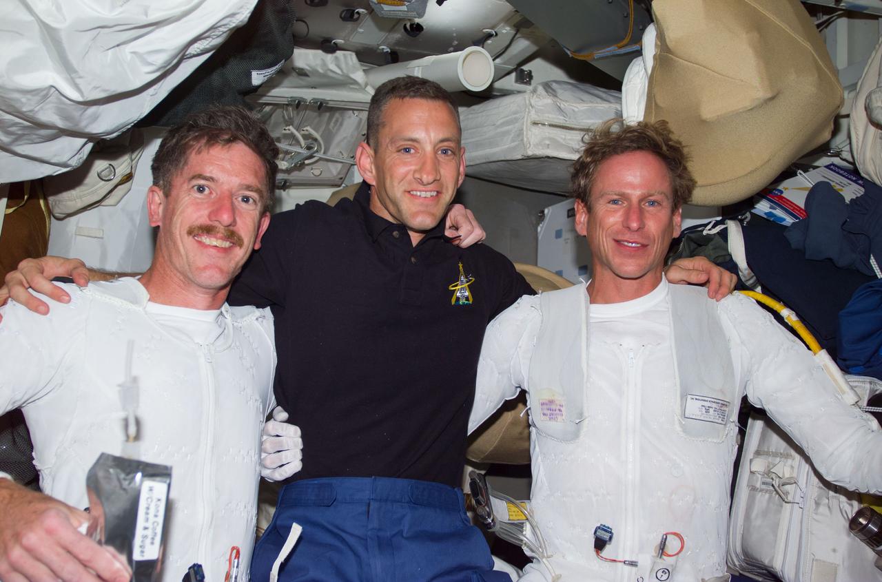 S104-E-5076 (15 July 2001) --- After completing the first extravehicular activity (EVA) of the STS-104 mission, James F. Reilly (left), mission specialist, and Michael L. Gernhardt (right), mission specialist, both wearing Liquid Cooling and Ventilation Garments (LCVG's), pose for a picture with Charles O. Hobaugh, pilot, on the middeck of the Space Shuttle Atlantis.