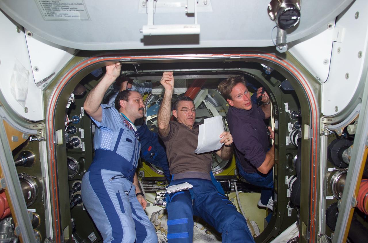 S104-E-5106 (16 July 2001) --- From left to right, cosmonaut Yury V. Usachev, Expedition Two mission commander, James S. Voss, Expedition Two flight engineer, and Michael L. Gernhardt, STS-104 mission specialist, discuss procedures for connecting cables and hoses from the newly installed Quest Airlock to Unity Node 1.  Usachev represents Rosaviakosmos.