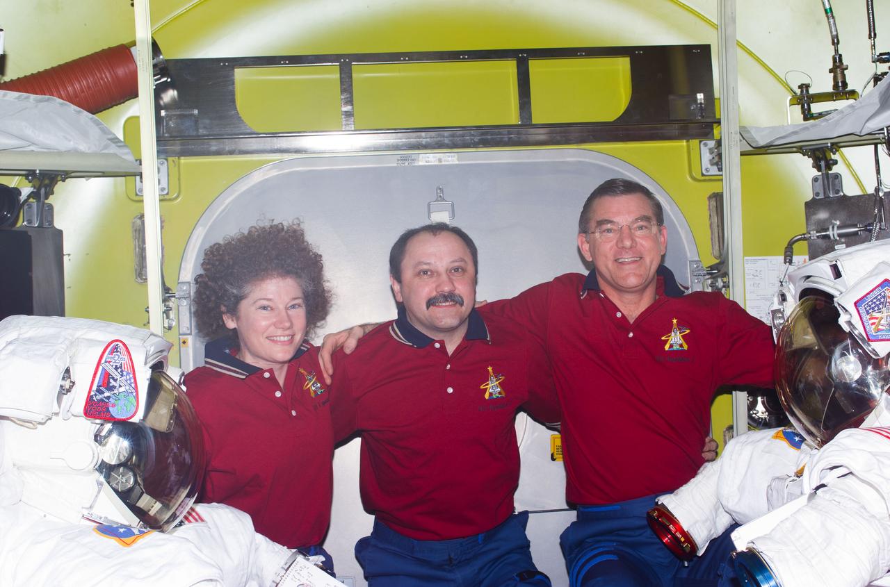 STS104-E-5188 (20 July 2001) --- The Expedition Two crew poses for an in-flight portrait in the newly- delivered Quest Airlock on the International Space Station (ISS). Flanked by two extravehicular mobility unit (EMU) space suits, are, from left, Susan J. Helms, Yury V. Usachev and James S. Voss.  Usachev is commander and Voss and Helms are both flight engineers. This image was recorded by one of the visiting STS-104 crew members using a digital still camera.