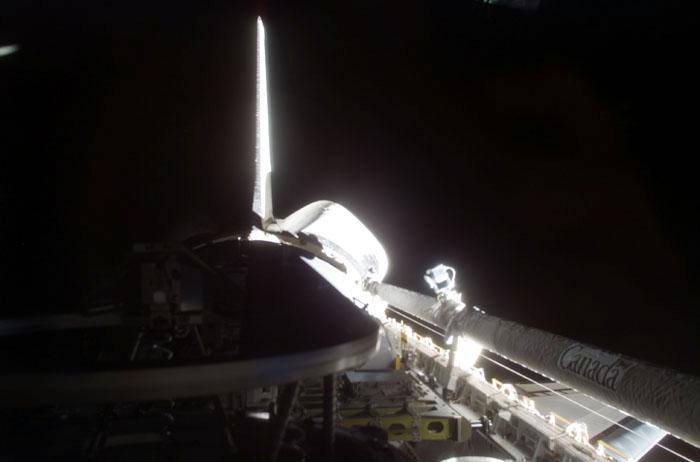 STS105-E-5037 (11 August 2001) --- One of the STS-105 crew members on the flight deck of the Earth-orbiting Space Shuttle Discovery used a digital still camera to record this image of the partially illuminated portside cargo bay and the silhouetted Orbiter Docking System's docking mechanism. The shuttle's Canadarm or Remote Manipulator System (RMS) arm is in its stowed position at right.