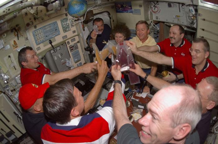 STS105-E-5200 (15 August 2001) --- Beverages are held high in a toast onboard the Zvezda Service Module of the International Space Station (ISS) as the astronauts and cosmonauts of STS-105 and Expedition Two and Expedition Three gather for one of their first joint meals. Nearest the digital camera's lens at lower right corner is astronaut Daniel T. Barry, STS-105 mission specialist.  Others, clockwise around the table, are astronauts Scott J. Horowitz, STS-105 commander; and Frederick W. Sturckow, STS-105 pilot;  cosmonauts Vladimir N. Dezhurov and Mikhail Tyurin, both Expedition Three flight engineers, Susan J. Helms, Expedition Two flight engineer, Frank L. Culbertson, Jr., Expedition Three commander; cosmonaut Yury V. Usachev, Expedition Two commander, and astronaut James S. Voss, Expedition Two flight engineer. Usachev, Dezhurov and Tyurin represent Rosaviakosmos. The image was recorded with a digital still camera.