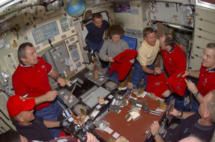 STS105-E-5201 (15 August 2001) --- Part of the &quot;dessert&quot; course for one of the first meals shared by the STS-105 and Expedition Two crews was the issuance of mission shirts for the departing station occupants.  Holding new jerseys in the Zvezda Service Module on the right side of the frame are astronauts Susan J. Helms and James S. Voss, departing flight engineers, and cosmonaut Yury V. Usachev, Expedition Two commander.  Clockwise from the lower left corner are astronaut Frederick W. (Rick) Sturckow, cosmonauts Vladimir Dezhurov and Mikhail Tyurin, Helms, astronaut Frank L. Culbertson, Jr., Usachev, Voss and astronaut Patrick G. Forrester. Astronauts Daniel T. Barry and Scott J. Horowitz are out of frame. Usachev, Dezhurov and Tyurin all represent Rosaviakosmos.  PLEASE NOTE: This event occurred on August 14, according to Central Daylight Time (CDT) but it was already the following day in Greenwich Mean Time (GMT).