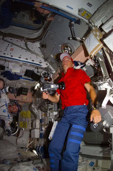 STS105-E-5364 (20 August 2001) --- Frederick W. Sturckow (center), STS-105 pilot, talks with Daniel T. Barry, mission specialist, in Unity Node 1.  In the background, Scott J. Horowitz, STS-105 commander, is trying on Vladimir N. Dezhurov's, Expedition Three flight engineer, Russian Sokol suit.  This image was taken with a digital still camera.