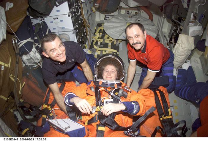 STS105-E-5442 (21 August 2001) --- As they near completion of their mission, the Expedition Two crew members prepare for the descent back to Earth.   Astronaut James S. Voss (left), flight engineer, and cosmonaut Yury V. Usachev (right), mission commander, strap astronaut Susan J. Helms, flight engineer, into her seat on the mid deck of the Space Shuttle Discovery.  Voss and Helms, representing NASA, and Usachev, representing Rosaviakosmos, are returning to Earth after completing their five-month assignment aboard the International Space Station (ISS).  This image was recorded with a digital still camera.