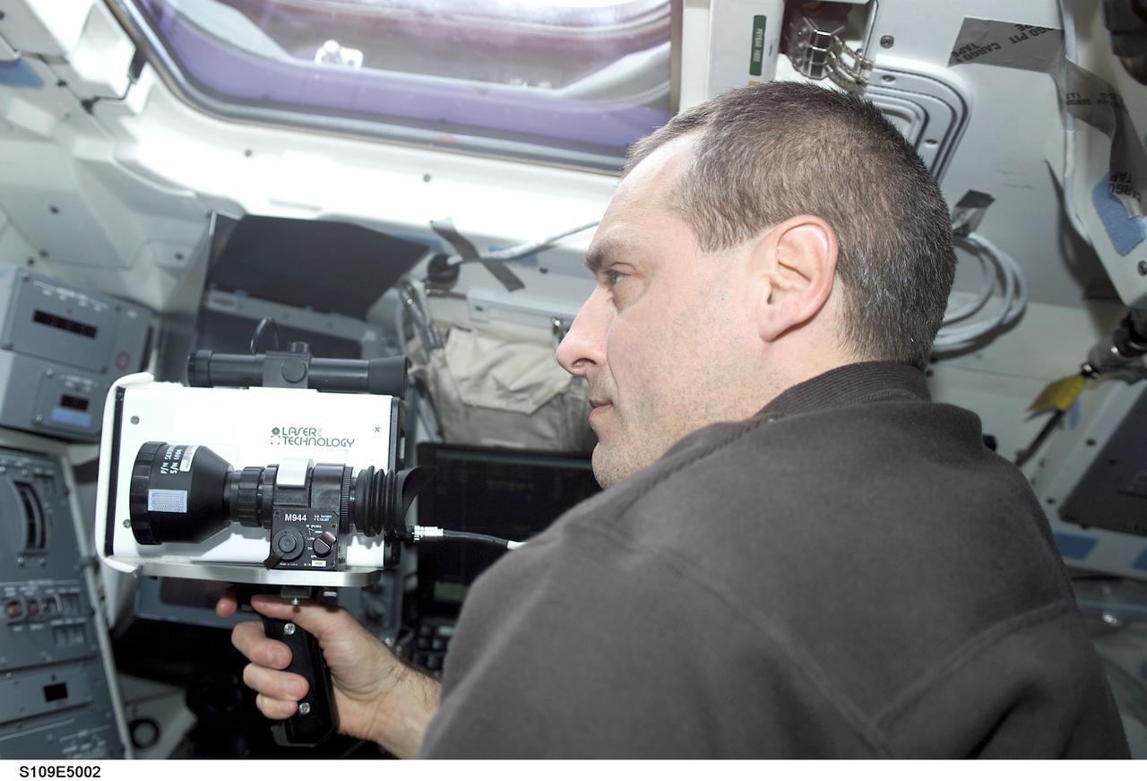 STS109-E-5002 (3 March 2002) --- Astronaut Richard M. Linnehan, mission specialist, uses a laser ranging device designed to measure the range between two spacecraft.  Linnehan positioned himself on the cabin's aft flight deck as the Space Shuttle Columbia approached  the Hubble Space Telescope.  A short time later, the STS-109 crew captured and latched down the giant telescope in the vehicle's cargo bay for several days of work on the Hubble.  The image was recorded with a digital still camera.