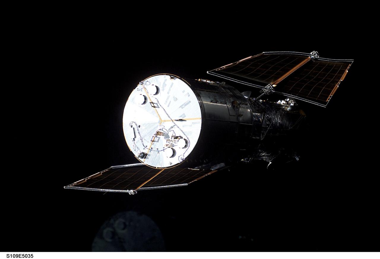 STS109-E-5035 (3 March 2002) --- The Hubble Space Telescope is visible against black space, primarily because its bright metallic disk-shaped base and the frame of its solar panels, as the Space Shuttle Columbia eases closer and closer in order to latch its 50-foot-long robotic arm onto a fixture on the giant telescope.  As Columbia flew 350 miles above the Pacific Ocean Southwest of  Mexico, with astronaut Nancy J. Currie, mission specialist, in control of the arm and astronaut Scott D. Altman, mission commander, at the  controls of the shuttle, the seven-member crew went on to capture the Hubble. The image was one of a series recorded with a digital still camera.