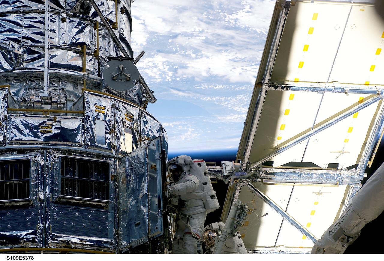 STS109-E-5378 (6 March 2002) ---  Astronaut John M. Grunsfeld, payload commander,  works in tandem with astronaut Richard M. Linnehan, mission specialist, as the two devote their attention to the Power Control Unit replacement task on the giant Hubble Space Telescope (HST). Grunsfeld stands on a foot restraint on the end of the Space Shuttle Columbia's Remote Manipulator System (RMS). This marked the third of five scheduled STS-109 space walks and the mission's second extravehicular activity (EVA) for the tandem of Grunsfeld and Linnehan. It was completed at 9:16 a.m. CST (1516 GMT), Mar. 6, 2002.  The image was recorded with a digital still camera.