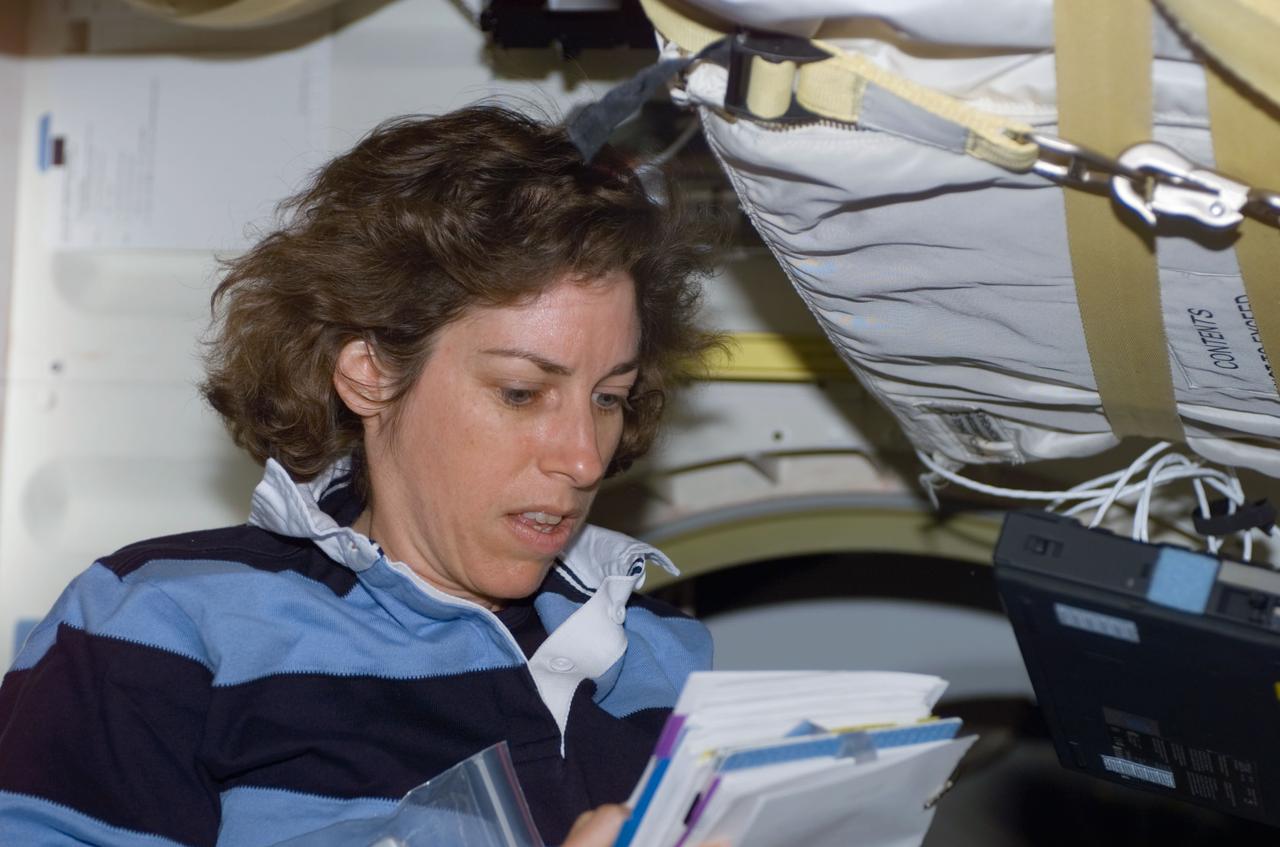 S110-E-5010 (8 April 2002) --- Astronaut Ellen Ochoa, STS-110 mission specialist, goes over a procedures checklist on the mid deck of the Space Shuttle Atlantis. The image was taken with at digital still camera.