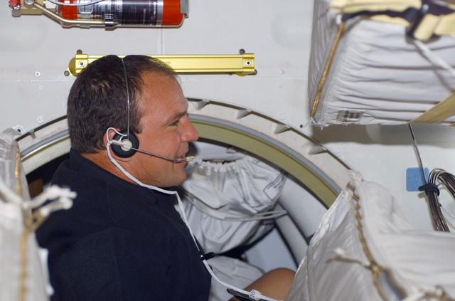 NASA image: Commander Bloomfield talks into a headset on the middeck of Atlantis during STS-110