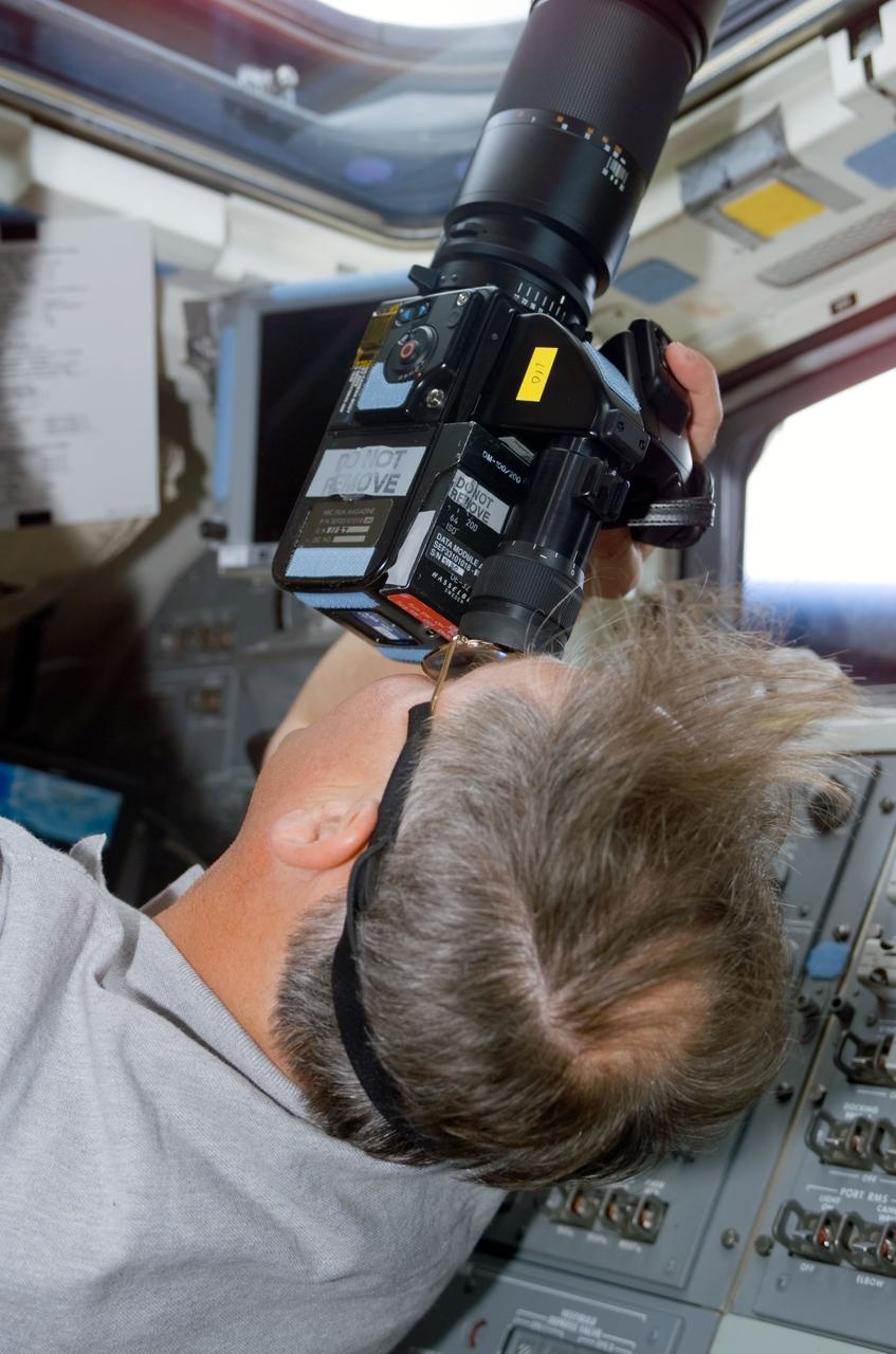 STS110-E-5050 (9 April 2002) --- Astronaut Jerry L. Ross, STS-110 mission specialist, takes photos out of an aft flight deck overhead window using a 70mm hand-held camera. The image was taken with a digital still camera.
