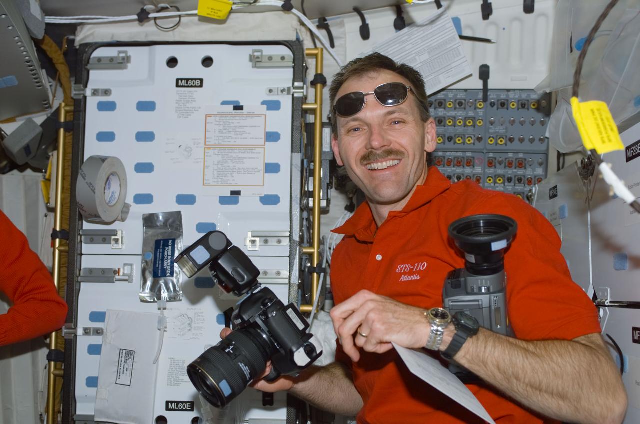 STS110-E-5088 (9 April 2002) --- Astronaut Steven L. Smith, STS-110 mission specialist, holds cameras on the mid deck of the Space Shuttle Atlantis. The image was taken with a digital still camera.