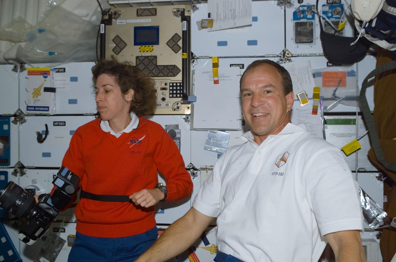 STS110-E-5091 (9 April 2002) --- Astronauts Ellen Ochoa (left) and Michael J. Bloomfield, STS-110 mission specialist and mission commander, respectively, are photographed on the mid deck of the Space Shuttle Atlantis. The image was taken with a digital still camera.
